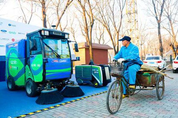Un employé chargé du nettoyage des rues sur son tricycle passe devant un véhicule nettoyeur sans pilote, le 20 décembre 2017 dans le district de Xuan'an, dans la province du Hebei (nord de la Chine). Photo Yan Yuxiao / le Quotidien du Peuple en ligne