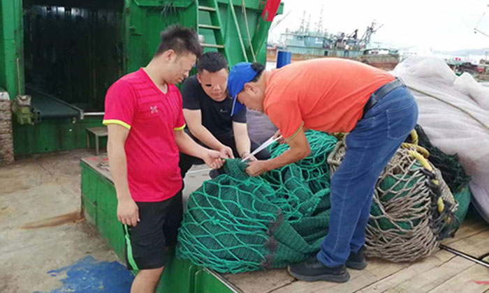 Des officiers de la Garde côtière chinoise montent à bord de bateaux de pêche pour inspecter les filets et le matériel de pêche. Photo : CCG